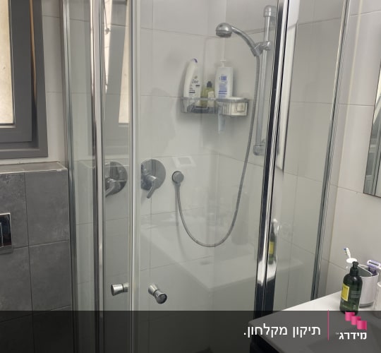 מקלחון זכוכית עם ראש מקלחת ומוצרי טיפוח
